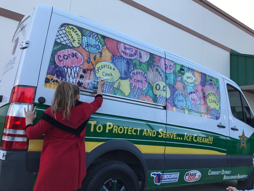 Alexandra Gleason, 9, signs her name on her design, which won first place for the Alachua County Sheriff’s Office’s ice cream truck. The truck’s design was unveiled Thursday as part of Operation CONE, which stands for Community Outreach Neighborhood Engagement.