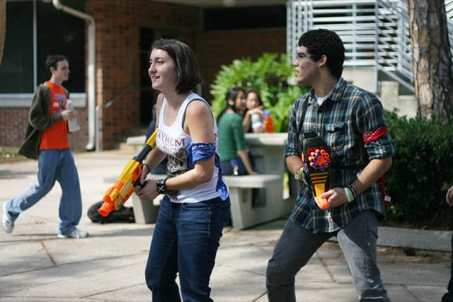 Megan Smith, 18, and Anthony Cardona, 19, keep on the lookout for zombies behind the Hub as part of the Human Vs. Zombies game.