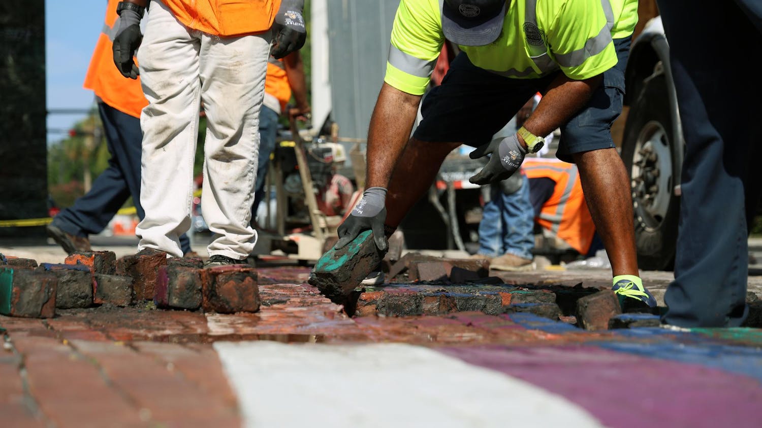 A City of Gainesville Public Works employee removes a green brick from the rainbow crosswalk on Northeast First Street to make room for new gray bricks on Monday, August 25, 2025.