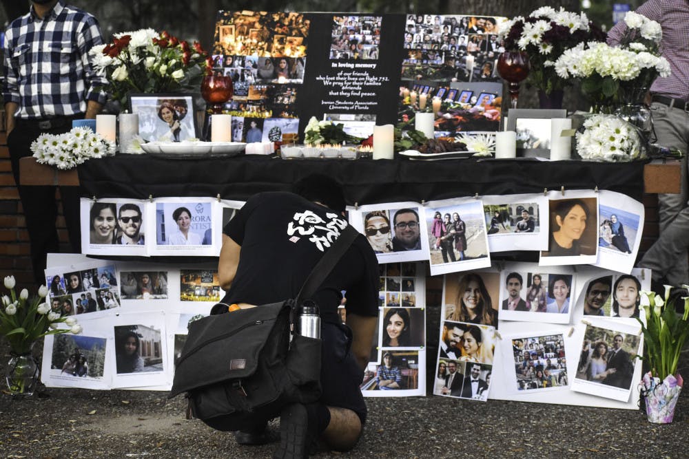 <p>A student passerby stops to honor the victims of a Ukrainian plane crash in Iran at a vigil put on by the Iranian Student Association in Turlington Plaza Tuesday afternoon.</p>
