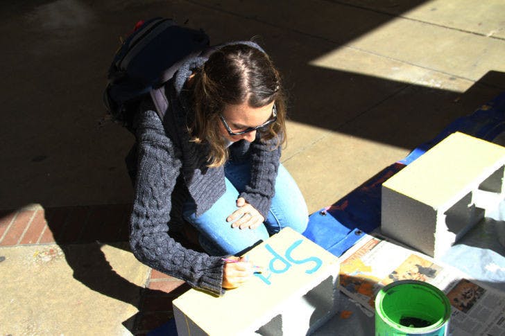 Alexandra Silverberg, a 21-year-old UF finance junior, decorates her brick for the Writing on the Wall Project 2014 on Thursday afternoon in front of Library West.