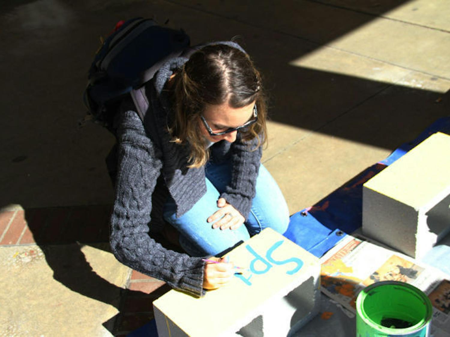 Alexandra Silverberg, a 21-year-old UF finance junior, decorates her brick for the Writing on the Wall Project 2014 on Thursday afternoon in front of Library West.