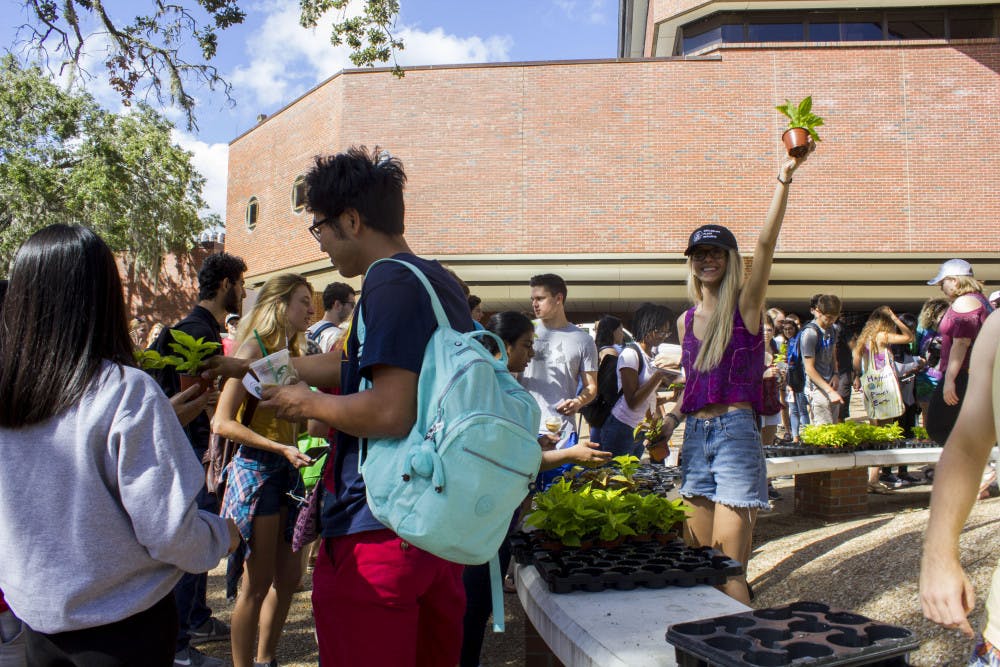 Grace Ebner, a volunteer and a TA for Plants, Gardens and You, passes out coleus plants to over 1,000 students in Turlington Plaza for Collegiate Plant Initiative.