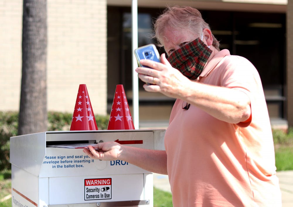 Linda Spurny takes a selfie with her ballot as she drops it off in front of the Alachua County Supervisor of Elections Office on Thursday, Oct. 15, 2020. She said she took the photo to insure it is counted. (Lauren Witte/Alligator Staff)