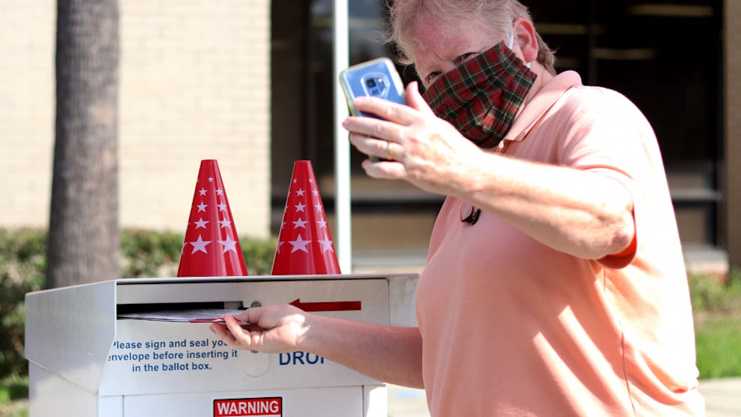 Linda Spurny takes a selfie with her ballot as she drops it off in front of the Alachua County Supervisor of Elections Office on Thursday, Oct. 15, 2020. She said she took the photo to insure it is counted. (Lauren Witte/Alligator Staff)