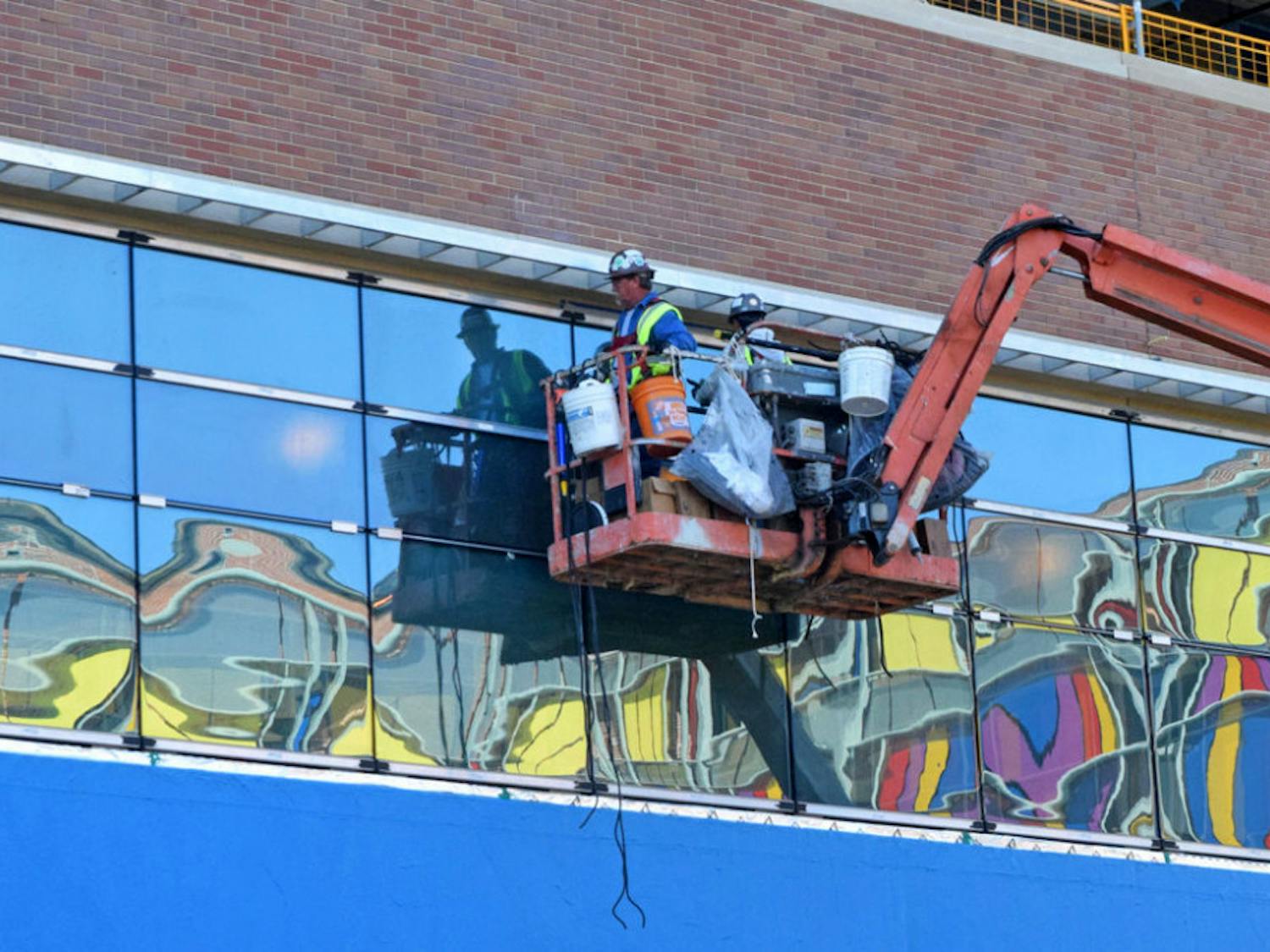 Construction workers fix window treatments on the new building of UF Health Shands Hospital on Wednesday. The children's hospital, across Archer Road, is reflected in the windows.
