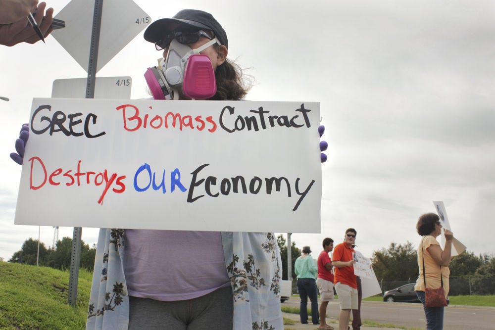 Maria Parsons, a Gainesville resident, protests at the corner of Northwest 39th Avenue and Northwest 97th Boulevard on Aug. 30, 2015. Her gas mask and gloves symbolize the pollution she said the biomass plant causes.