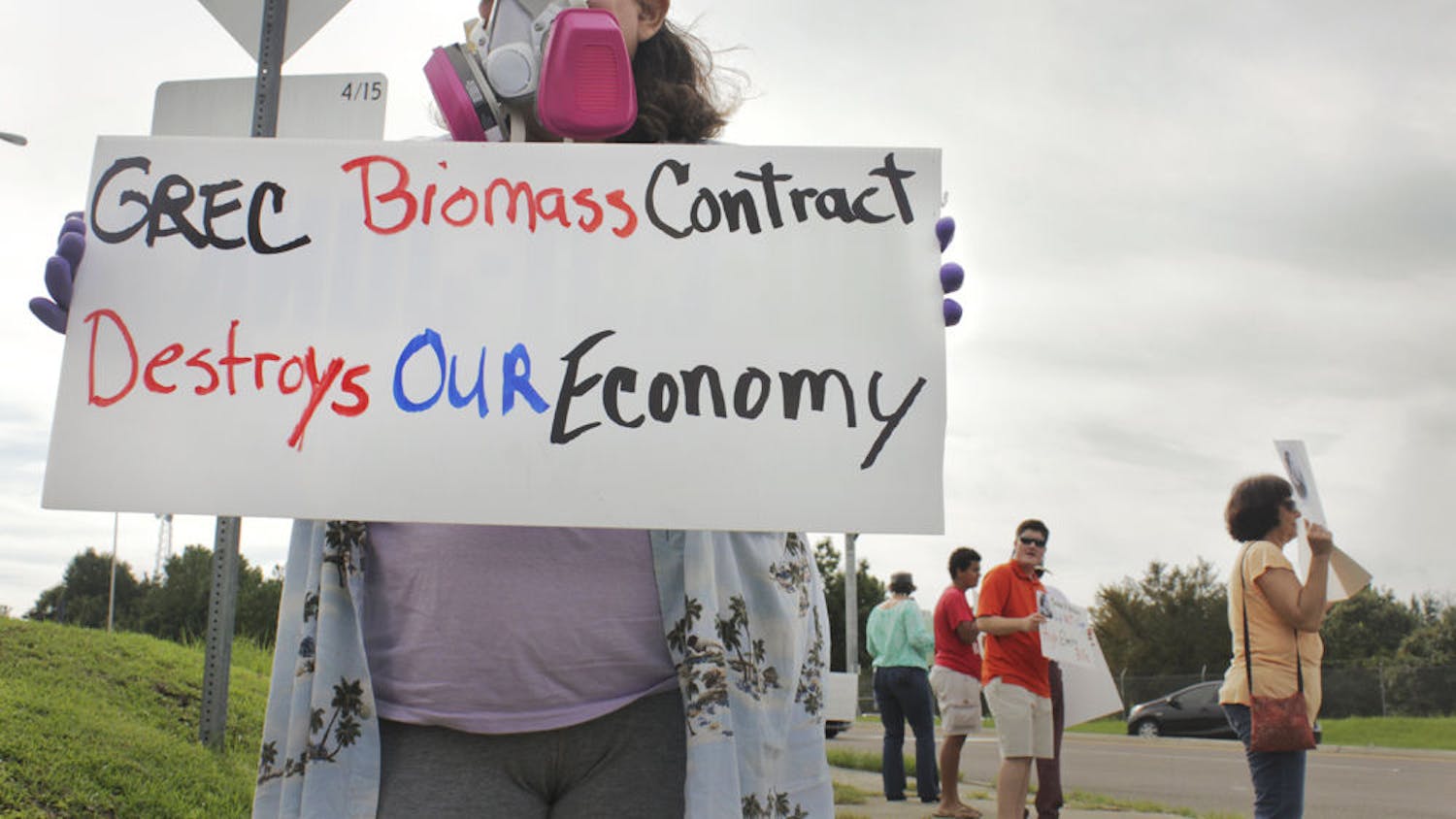 Maria Parsons, a Gainesville resident, protests at the corner of Northwest 39th Avenue and Northwest 97th Boulevard on Aug. 30, 2015. Her gas mask and gloves symbolize the pollution she said the biomass plant causes.