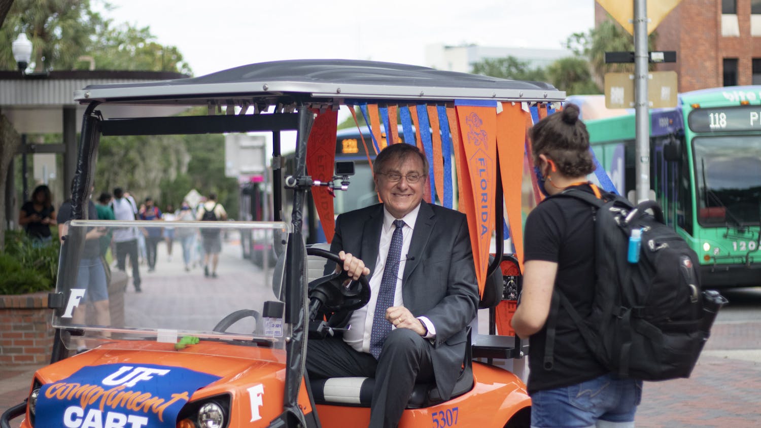 President Fuchs stops to speak to Ally Fleischer, 21, UF criminology and family youth and communication sciences senior, while driving the UF Compliment Cart around campus on the first day of Fall semester, Monday, Aug. 23, 2021. Fleischer took a selfie with Fuchs on her first day of freshman year, too. When asked about the Fall semester, Fleischer said "I'm excited. I haven't been to class in 524 days."