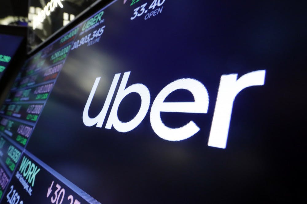 FILE - In this Friday, Aug. 16, 2019 file photo, the logo for Uber appears above a trading post on the floor of the New York Stock Exchange. The Ride-hailing service is acquiring Cornershop as it tries to gain a foothold in the Latin American grocery delivery business. San Francisco-based Uber, whose $5.24 billion loss last quarter was its largest ever, has been expanding its offerings to include food delivery and other forms of transportation, such as scooters and bikes. (AP Photo/Richard Drew, file)