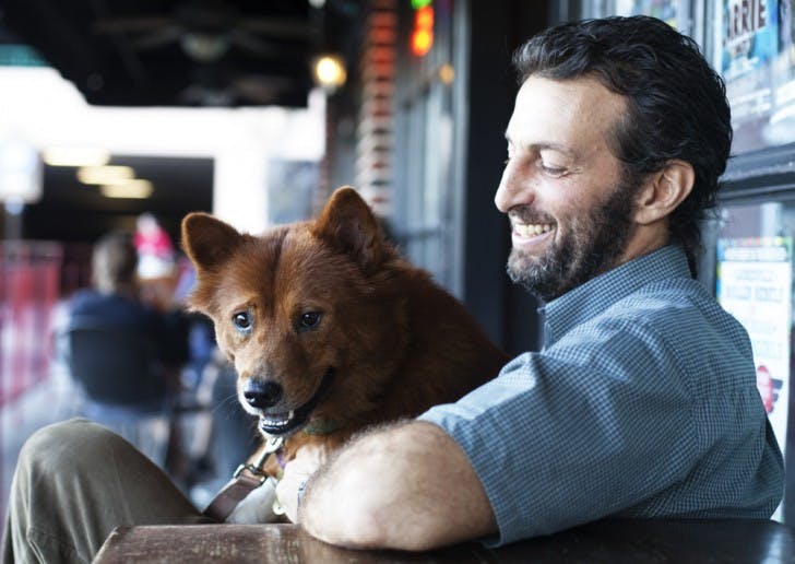 Mushi, a 3-year-old Chow Chow mix, sits on Dan Kahn’s lap and looks at passersby outside Loosey’s in downtown Gainesville on Tuesday, two weeks after being hit by a car.