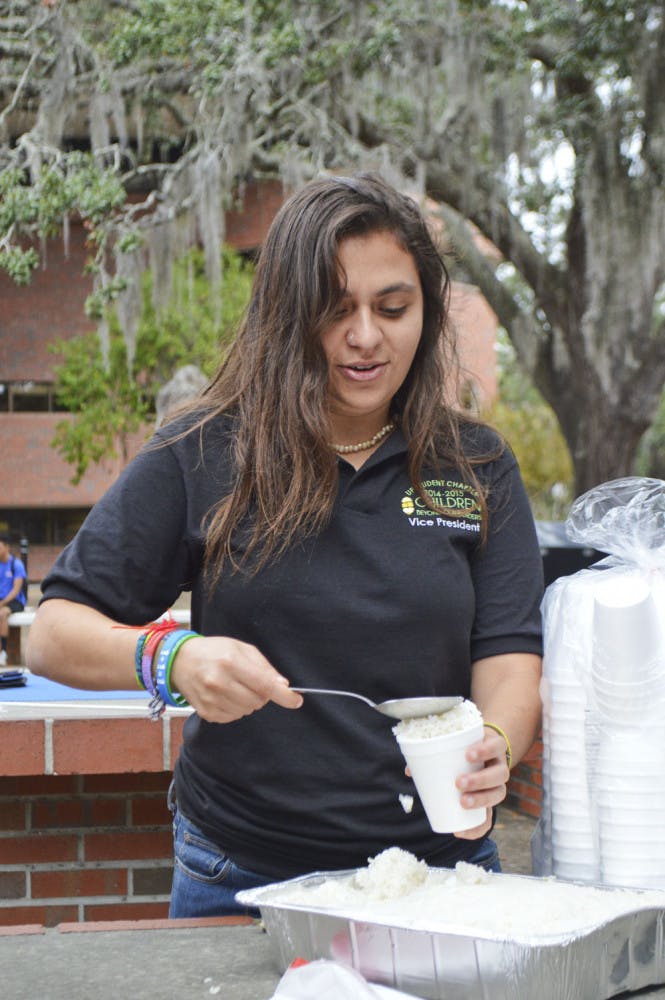 Alicia Leva, a 21-year-old UF international studies senior, prepares a cup of rice Monday morning. Children Beyond Our Borders held the event on Turlington Plaza in solidarity with those living through hunger.