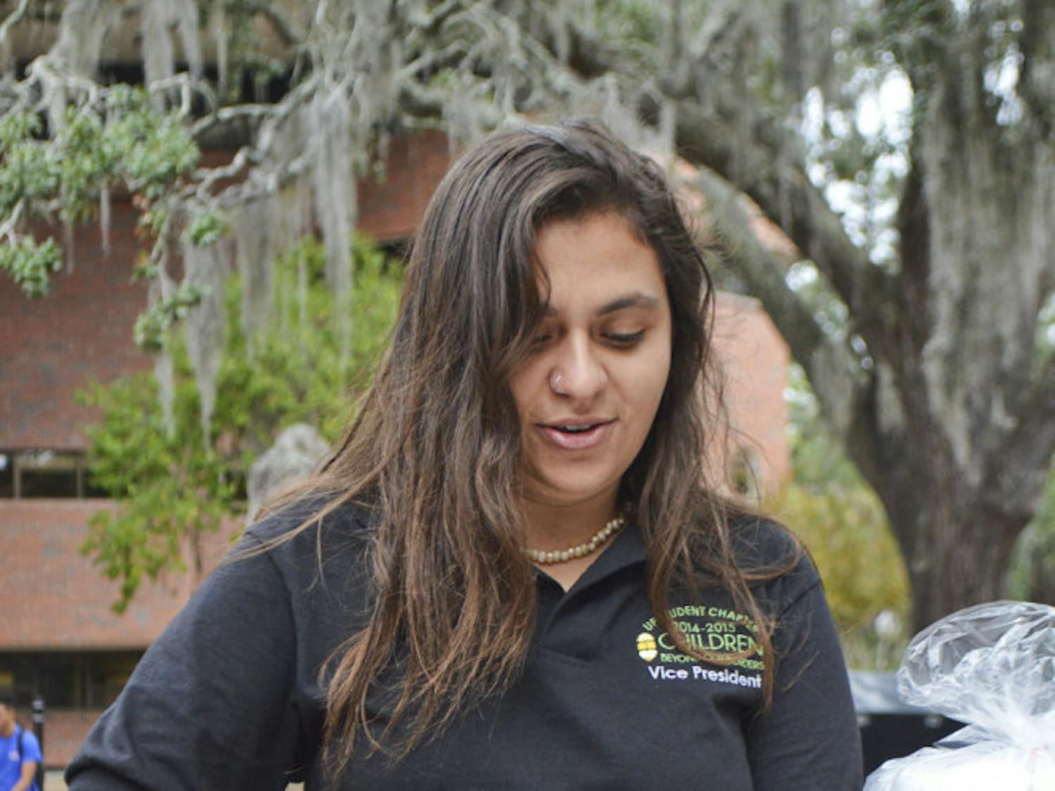 Alicia Leva, a 21-year-old UF international studies senior, prepares a cup of rice Monday morning. Children Beyond Our Borders held the event on Turlington Plaza in solidarity with those living through hunger.
