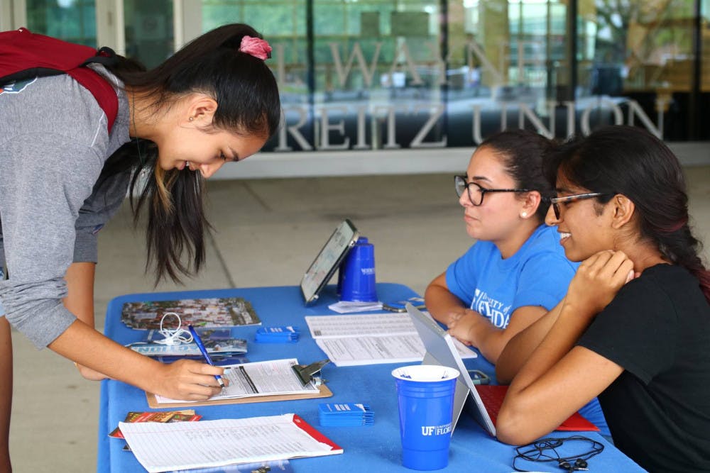 Bob Graham Center for Public Service student fellows Priya Amilineni (right) and Dalia Figueredo (center) register a student to vote during the July 19 voter registration event in coordination with the Alachua County Supervisor of Elections. 
