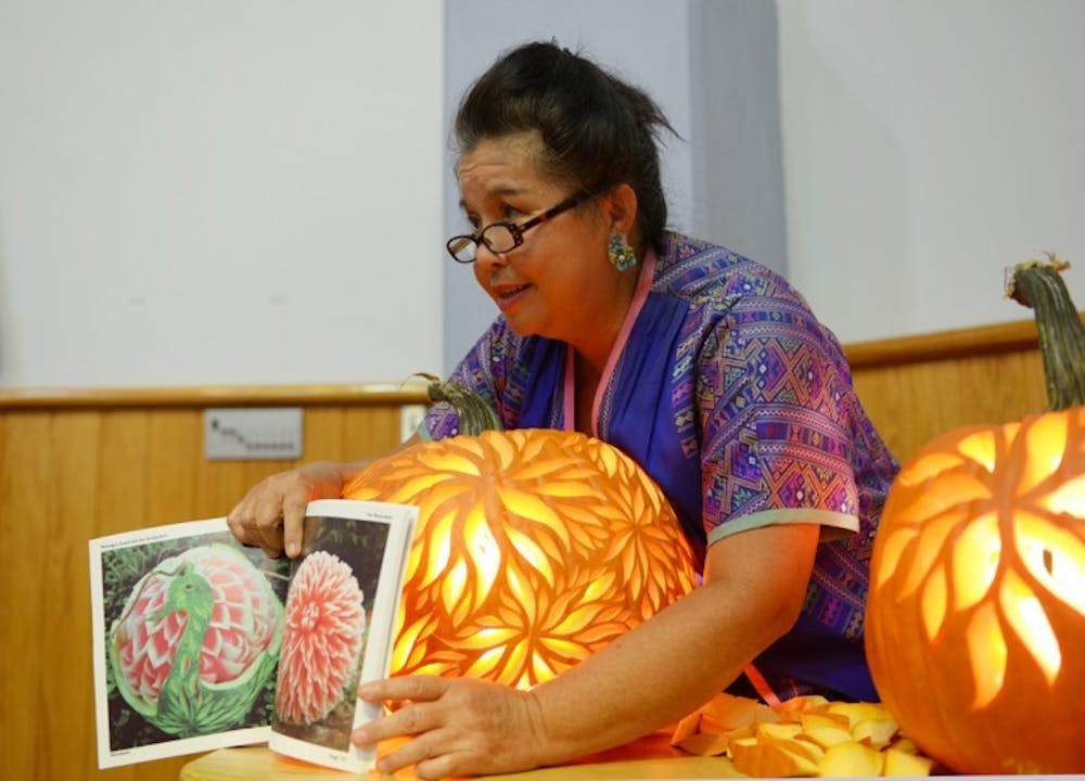 <p>Kae-Sa-Luk Master Pam Maneeratana, 60, shows off her book, 'Messages Found with the Carving Knife', during a carving demonstration at the Alachua County Headquarters Library on Saturday. Maneeratana was trained by an instructor from the Royal Palace in Thailand as a child and has been carving professionally for over 30 years.</p>