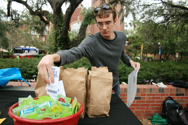 A student distributes free condoms from GatorWell on Turlington Plaza.