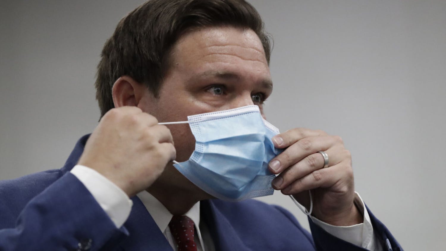 Florida Gov. Ron DeSantis puts on his mask as he leaves a news conference at Jackson Memorial Hospital, Monday, July 13, 2020, in Miami. DeSantis acknowledged Monday that the new coronavirus is spreading and urged people to take precautions such as wearing masks in public places, social distancing and avoiding crowds. (AP Photo/Wilfredo Lee)