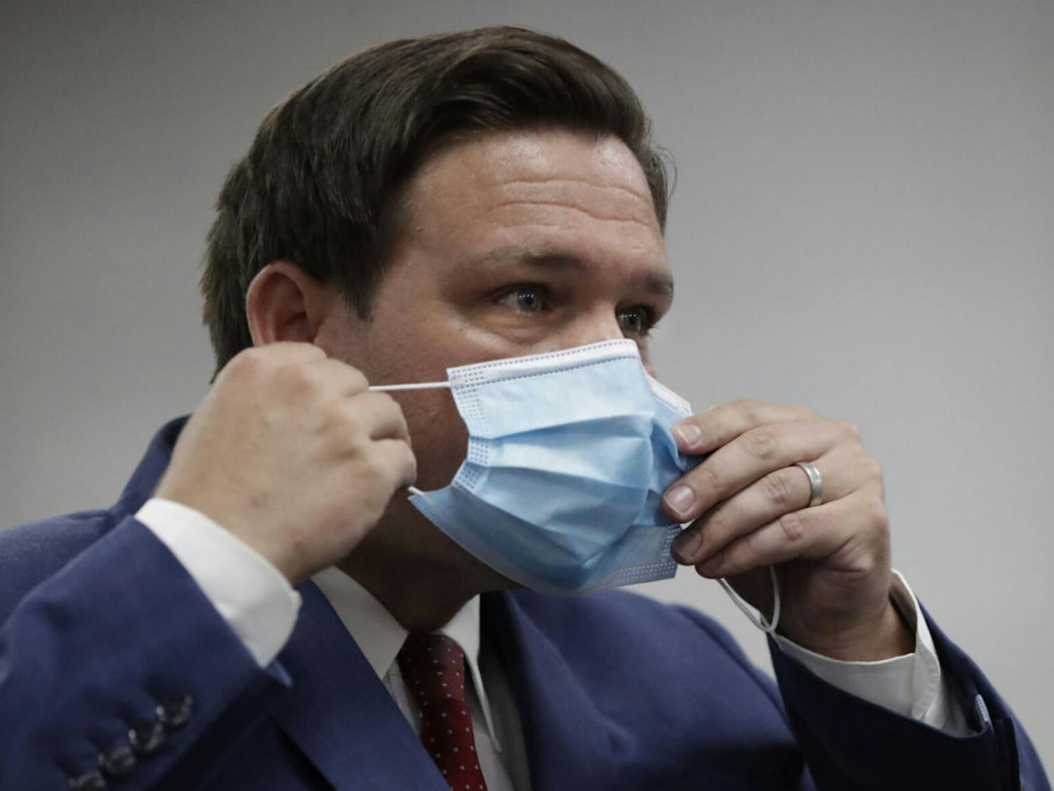 Florida Gov. Ron DeSantis puts on his mask as he leaves a news conference at Jackson Memorial Hospital, Monday, July 13, 2020, in Miami. DeSantis acknowledged Monday that the new coronavirus is spreading and urged people to take precautions such as wearing masks in public places, social distancing and avoiding crowds. (AP Photo/Wilfredo Lee)