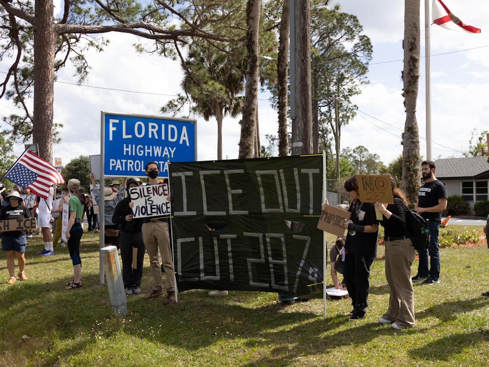Protestors hold signs outside Florida Highway Patrol station, Friday, April 3, 2026, in Gainesville, Fla.