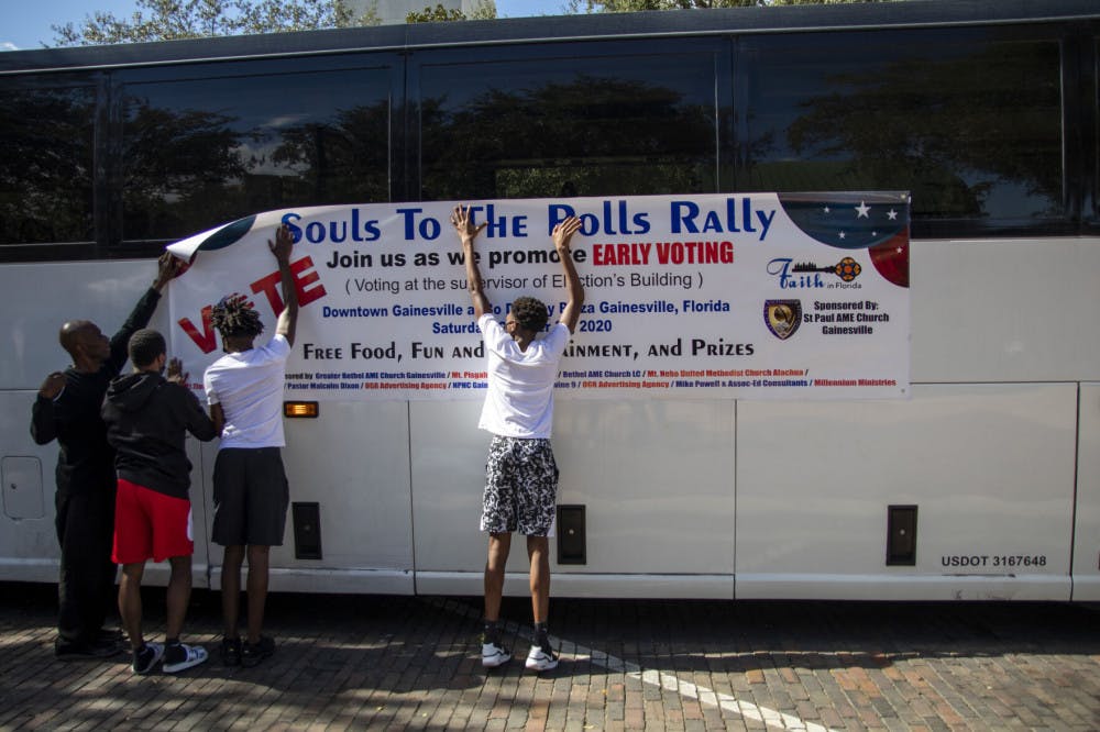 Volunteers put up a “Souls to The Polls” banner on a bus that takes people from Bo Diddley Plaza to the Alachua County Supervisor of Elections office on Saturday, Oct. 31, 2020.&nbsp;