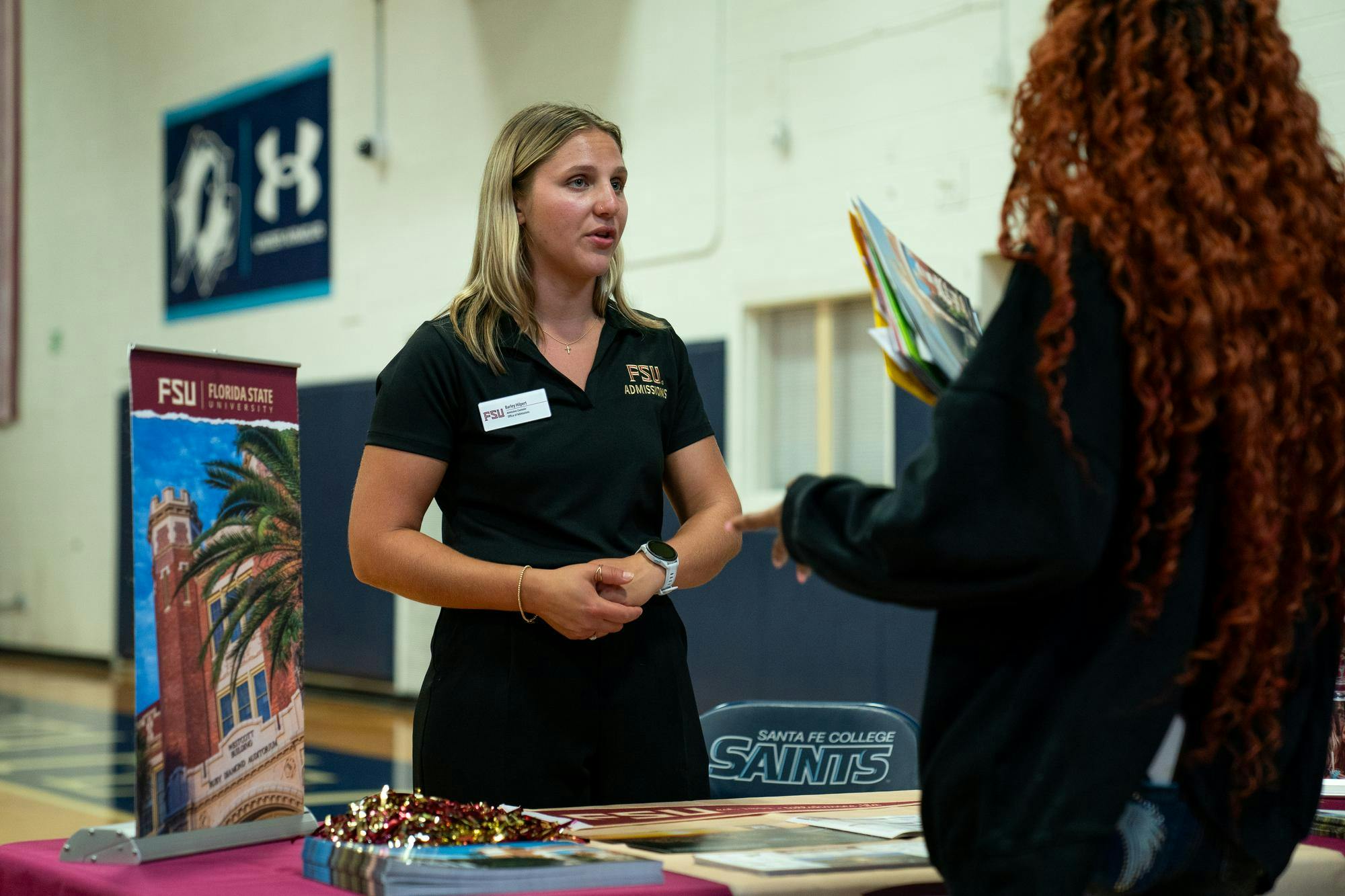Barley Hilpert from Florida State University talks with an attendee during a college fair, Monday, Aug. 31, 2026 at Santa Fe College in Gainesville, Fla.
