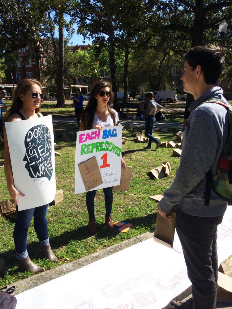 Michelle Smith, a 20-year-old UF health science sophomore, and Christine Marino, a 21-year-old UF health education and behavior junior, talk to Joseph Buss, a 19-year-old UF economics sophomore, during Alpha Epsilon Delta’s “Every Gator Counts” event. The pre-health honor society passed out 400 paper bags holding anonymous stories of AED members’ struggles with mental illness to let students know they’re not alone.