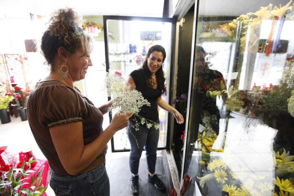 <p>Jennifer Russo, 46, left, and Ridgely Fanara, 38, right, gather flowers for floral arrangements in Gainesville Floral Exchange, 635 NW 13th Street, Suite C, Tuesday afternoon.</p>