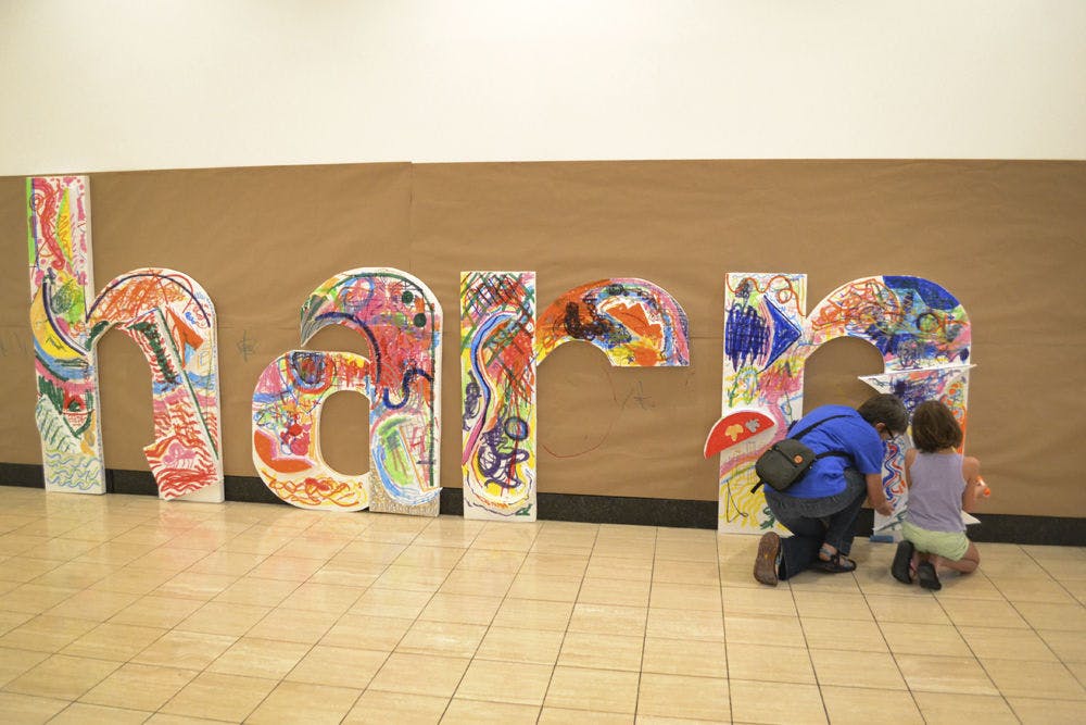 <p>Marta Wayne (left), 49, and her daughter Norma Wayne, 9, draw on foam letters at the Samuel P. Harn Museum of Art’s 25th anniversary public celebration on Sept. 27, 2015. Visitors drew on the letters throughout the day. The concept was based on the sculpture “Zandvoort” by Frank Stella.</p>