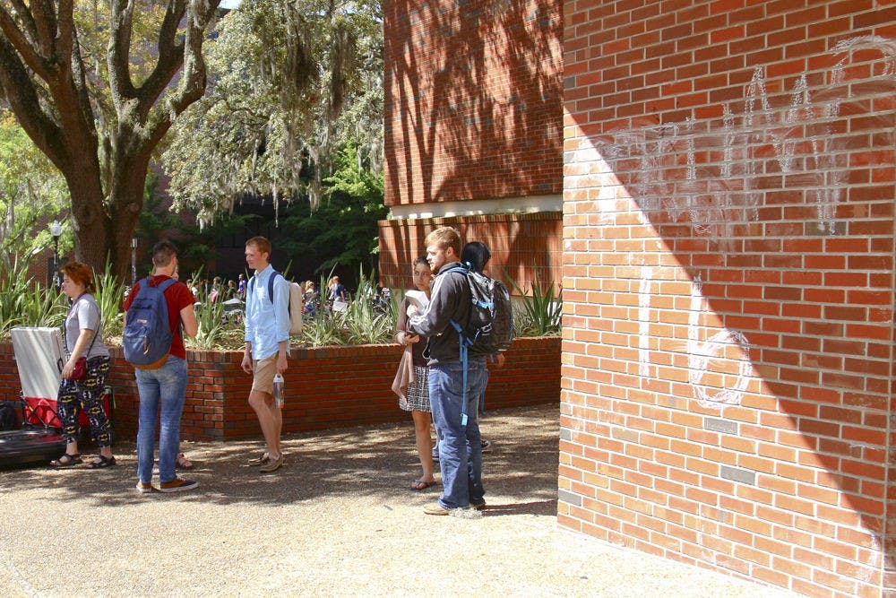 <p>Students pass by a “Trump 16” sign chalked into the wall of Turlington Plaza on Monday. The sign was a part of a nationwide April Fool’s contest organized by entertainment website and forum Old Row, which asked students to chalk pro-Trump messages across their campuses.</p>