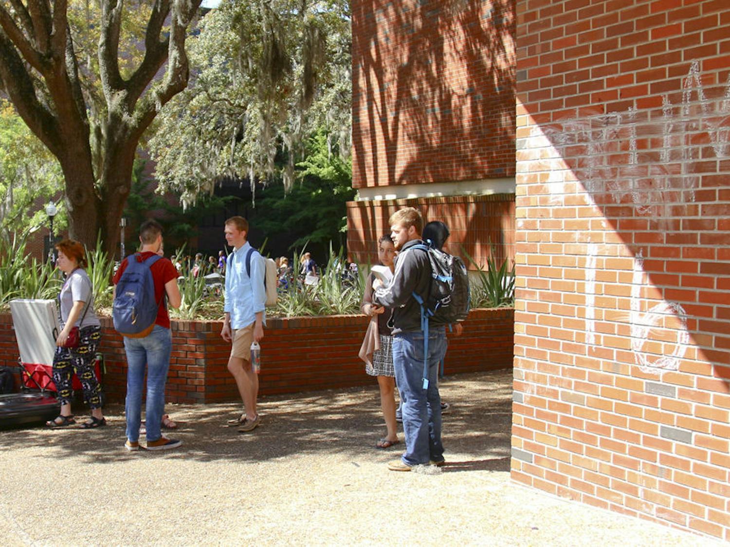 Students pass by a “Trump 16” sign chalked into the wall of Turlington Plaza on Monday. The sign was a part of a nationwide April Fool’s contest organized by entertainment website and forum Old Row, which asked students to chalk pro-Trump messages across their campuses.
