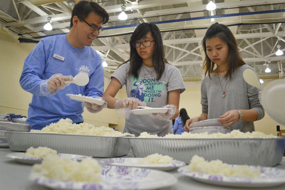 <p>(From left) Kevin Sardja, a 21-year-old UF finance junior; Rebekah Kim, a 19-year-old UF physics sophomore and Candice Luc, a 19-year-old UF civil engineering sophomore, divide rice onto the plates students would use to carry food at Asian Kaleidoscope Month’s 23rd annual Food Festival.</p>