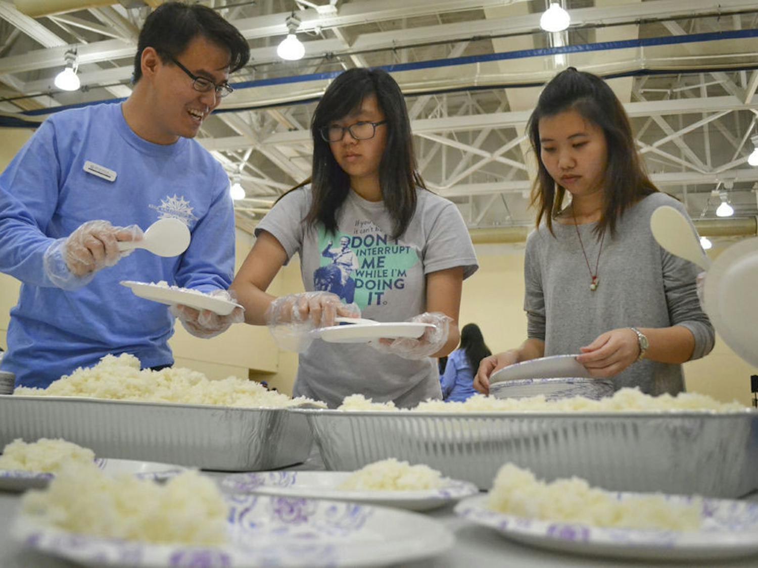 (From left) Kevin Sardja, a 21-year-old UF finance junior; Rebekah Kim, a 19-year-old UF physics sophomore and Candice Luc, a 19-year-old UF civil engineering sophomore, divide rice onto the plates students would use to carry food at Asian Kaleidoscope Month’s 23rd annual Food Festival.