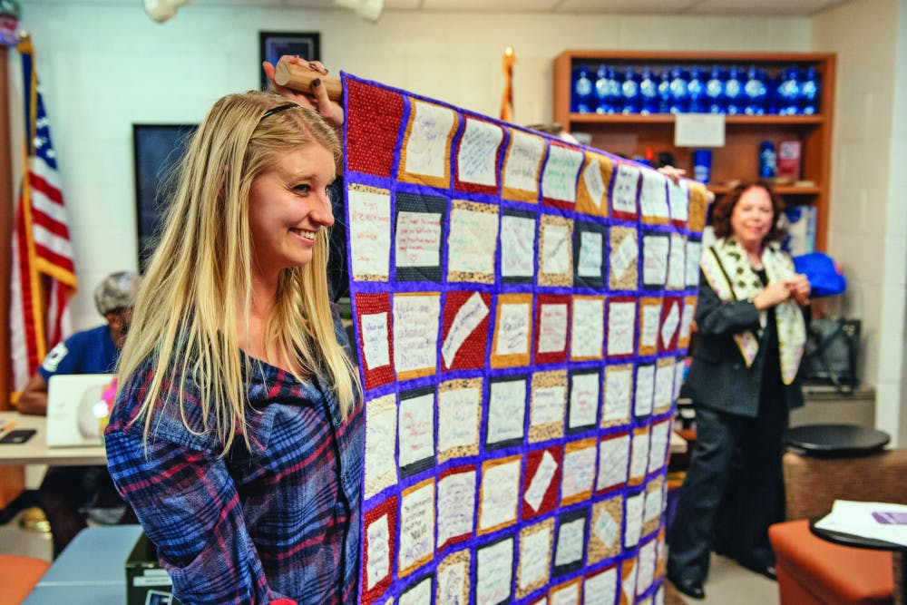 Paige Arnold, a 24-year-old UF public relations senior, holds up a quilt with UF professor Deanna Pelfrey at a Collegiate Veterans Society meeting on Thursday. Each patch on the quilt has a note from a UF undergraduate student to a veteran.