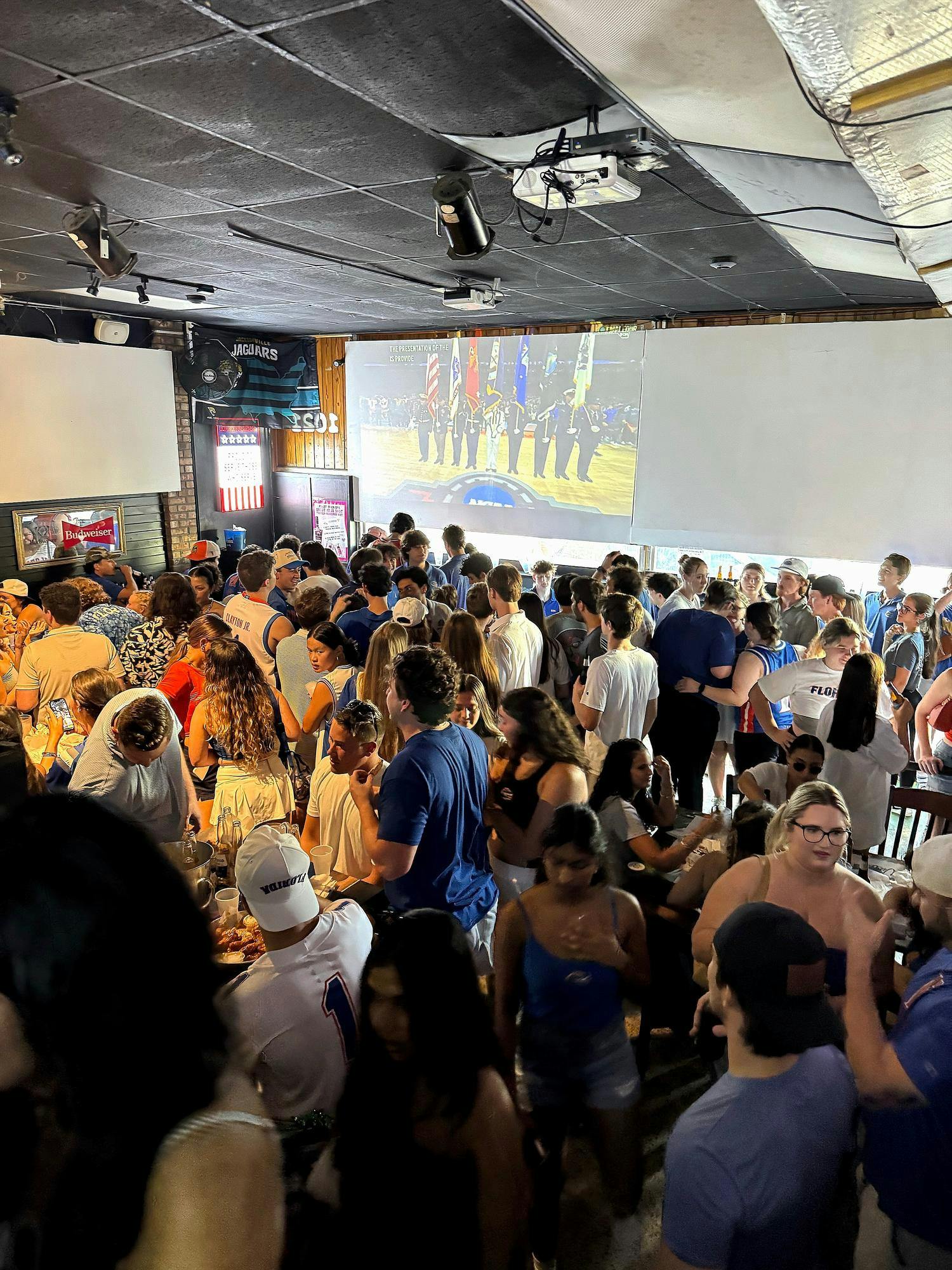 A crowd gathers in front of the screen at Mom's OG Bar and Grill in Gainesville, Fla.