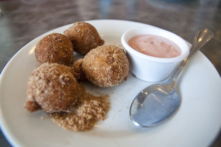 The Apple Fritters at Peach Valley Cafe are brought to the table in a brown paper bag, shaken up in sugar and cinnamon and served on a plate with a yogurt dipping sauce.