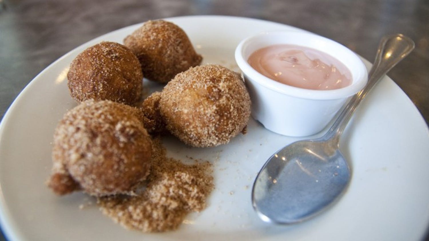 The Apple Fritters at Peach Valley Cafe are brought to the table in a brown paper bag, shaken up in sugar and cinnamon and served on a plate with a yogurt dipping sauce.