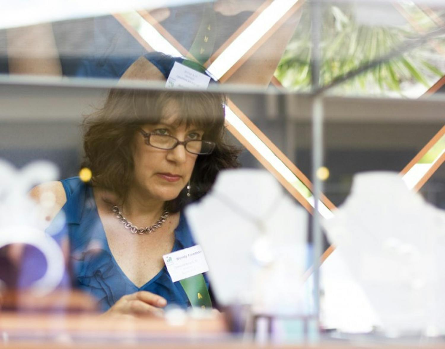 Wendy Foreman, a 51-year-old jeweler from Ormond Beach, Fla., peers over her display at the Gainesville Fine Arts Association's 28th annual GFAA Art Festival at Thornebrook over the weekend at 2441 NW 43rd Street.