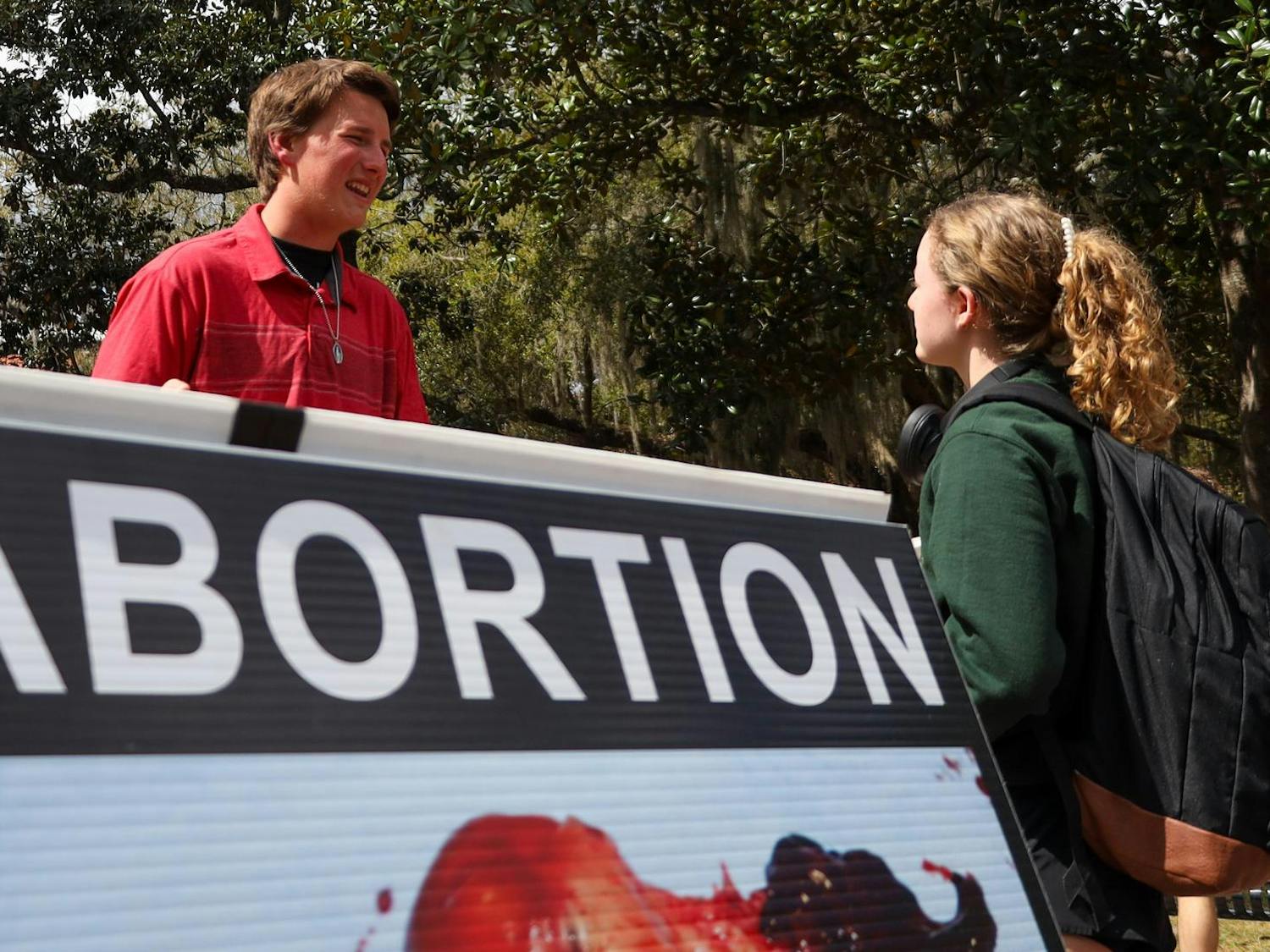 Madoc, a high-schooler from Columbus, OH, shares pamphlets about abortion to UF students on Plaza of the Americas, March 6, 2026 in Gainesville, Fla.