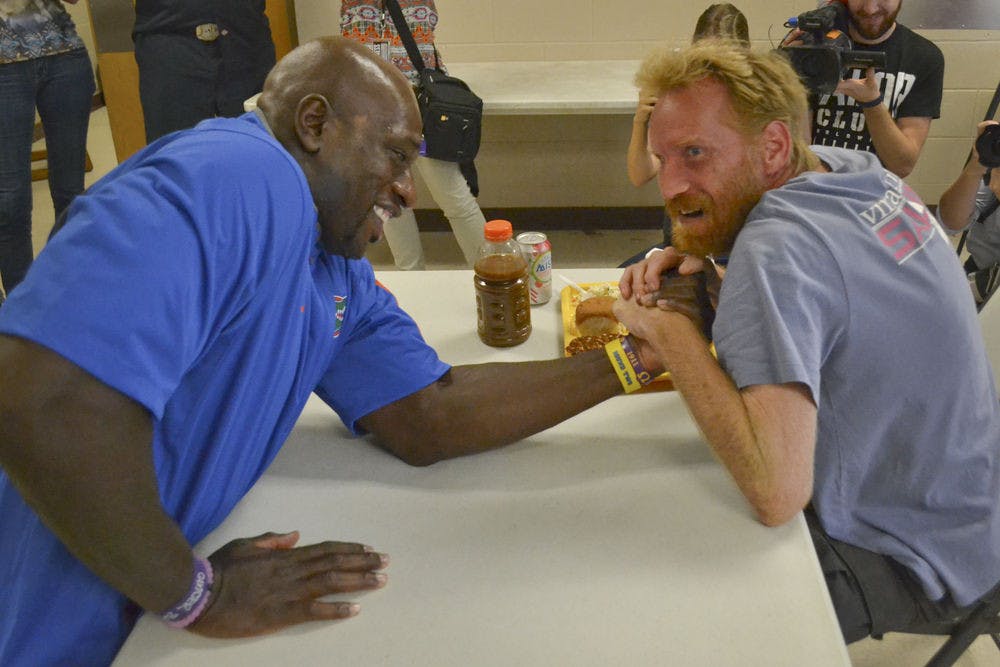 <p>Thaddeus Bullard (left), also known as WWE wrestler Titus O’Neil, arm wrestles Mike Grace, a 38-year-old homeless veteran, at St. Francis House on Oct. 2, 2015. Grace challenged Bullard to the match and won. “I imagine he could pick me up and throw me across the room,” Grace said about Bullard.</p>