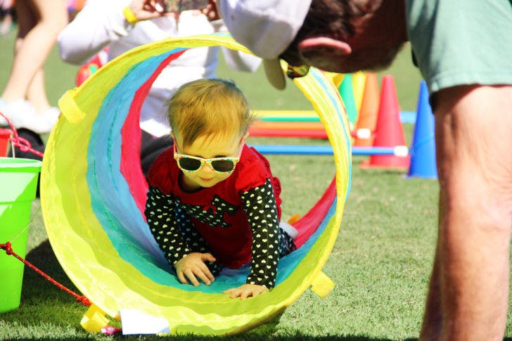 Aria Cole, 1, crawls to her grandfather, Tim Jallen, 62, through a play tunnel at UF’s fifth annual Stomp the Swamp for Autism fitness event Saturday at Ben Hill Griffin Stadium.