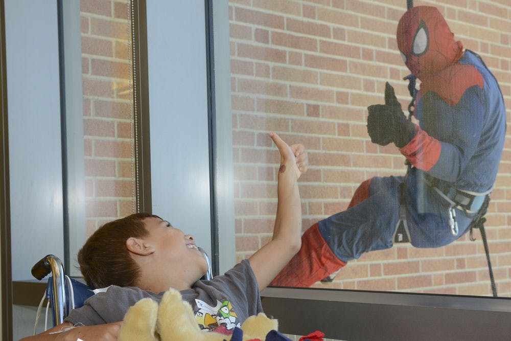 Dave Krieger (right), an Aurora SWAT team leader dressed as Spiderman, rappels down the side of Children’s Hospital Colorado August 12, 2015.