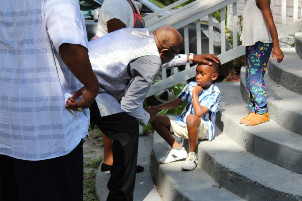 Chris Stokes consoles a young parishioner before church on Sunday. The boy soon rose and walked inside.