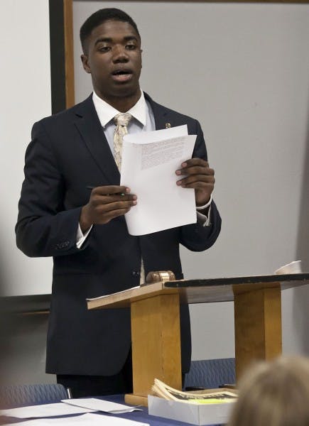 STUDENT SENATE -- Senate President Aundre Price provides copies of Rule XIII Censure, Expulsion and Officer Removal Tuesday at UF's Senate meeting after receiving complaints about senator behavior during the meeting May 29. He told senators to follow the procedures described in the rules if he or she wishes for another senator to be censored or removed.