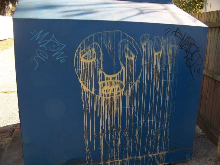 Graffiti appears on a trash bin in the parking lot of The Courtyards apartment complex.