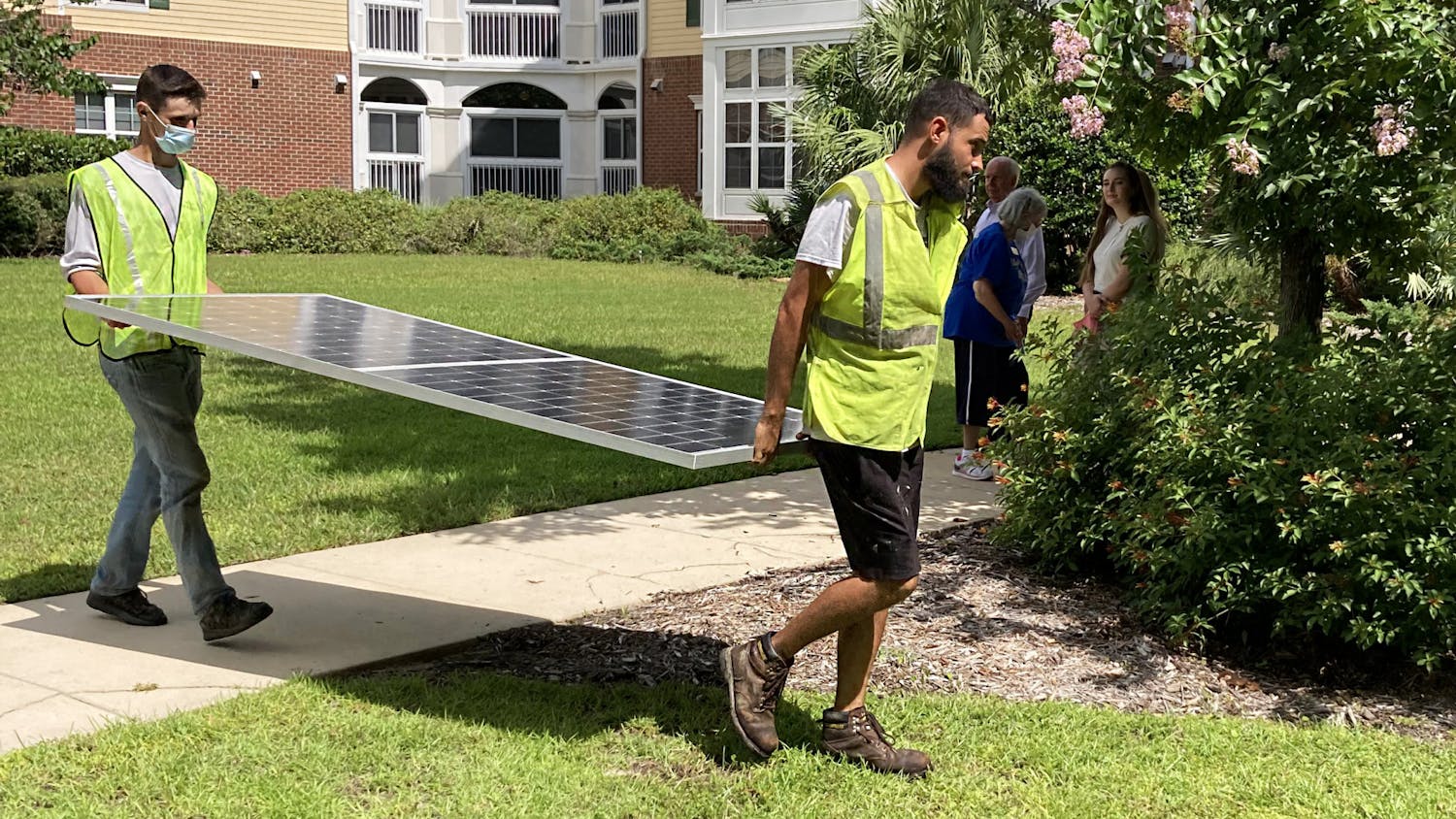 Workers lift up the first solar panel installed on the rooftops of Oak Hammock at the University of Florida on Tuesday, July 20, 2021. 