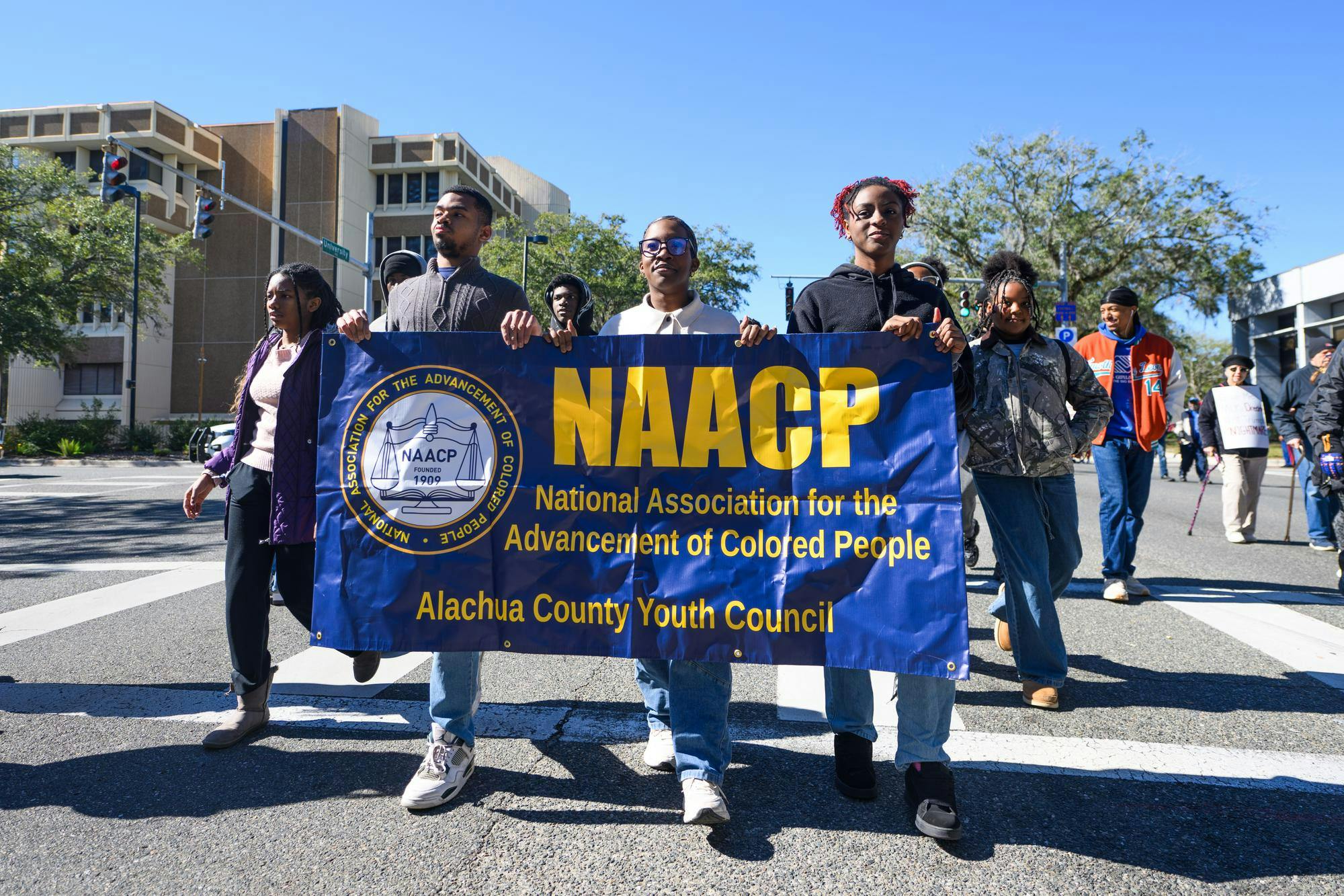 Parade participants carry a sign for the Alachua County NAACP Youth Council during Gainesville's MLK Day Parade, Monday, Jan. 19, 2026.