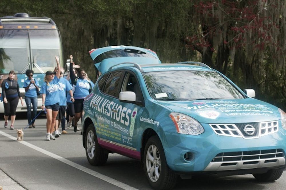 <p>Lauren Book, founder of Lauren's Kids, and her supporters wave at passing motorists at they walk down Museum Drive near Lake Alice on Tuesday as part of the "Walk in My Shoes" campaign, which is a 1,500 mile walk across Florida to bring awareness to help prevent sexual abuse.</p>