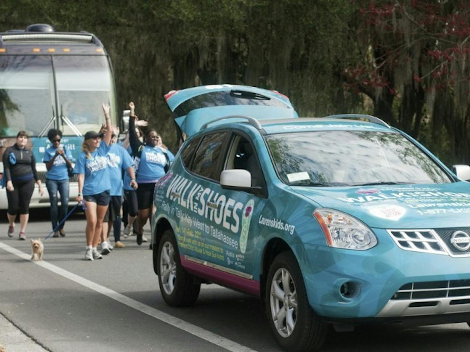 Lauren Book, founder of Lauren's Kids, and her supporters wave at passing motorists at they walk down Museum Drive near Lake Alice on Tuesday as part of the "Walk in My Shoes" campaign, which is a 1,500 mile walk across Florida to bring awareness to help prevent sexual abuse.