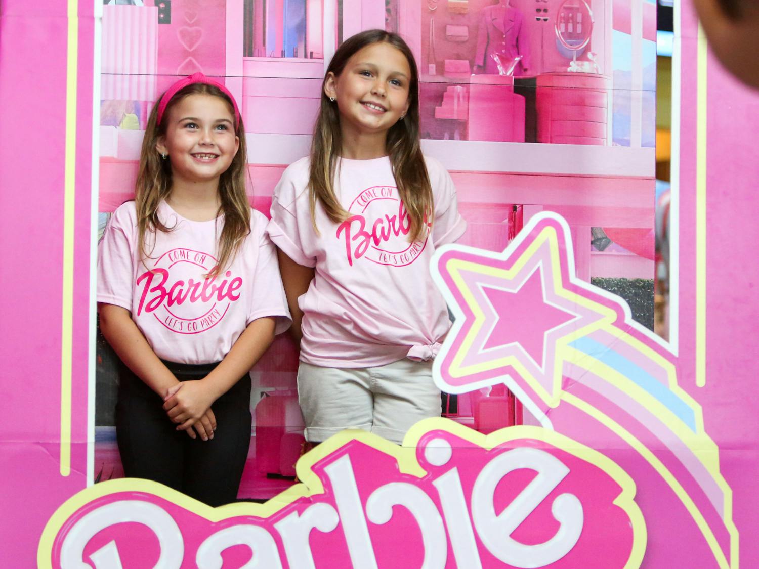 The Wirick sisters pose for their mom in a promotional life-size Barbie doll box at Regal Celebration Pointe on Wednesday, July 19, 2023.