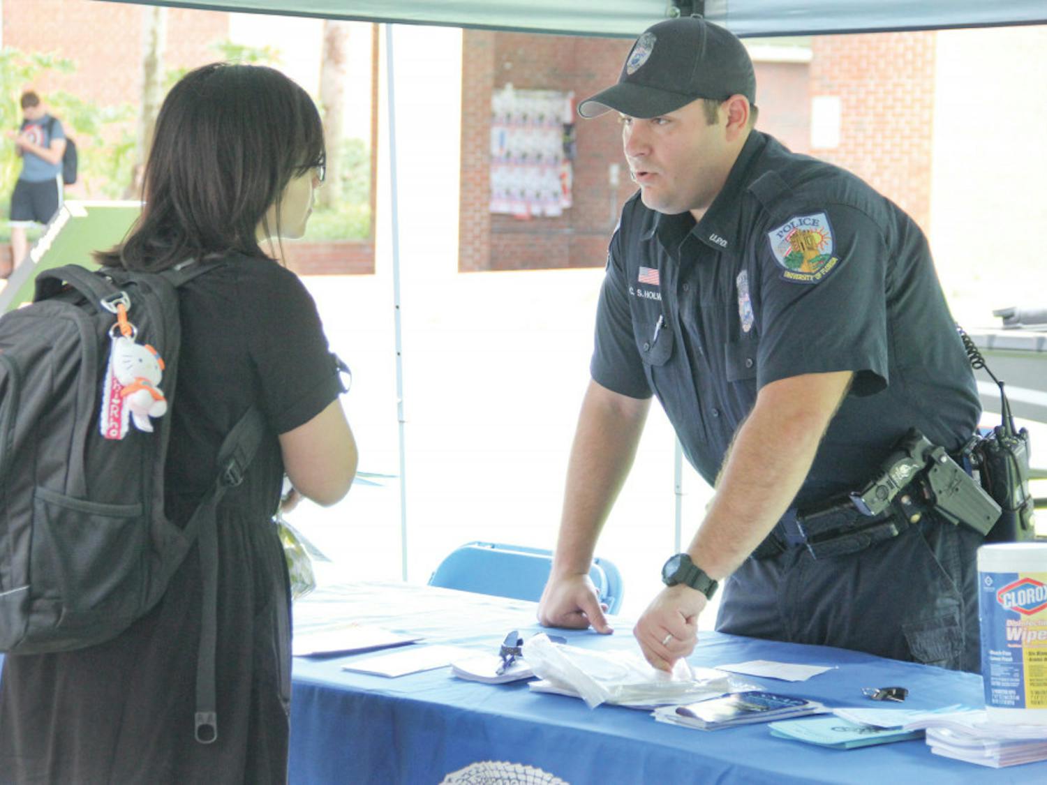 University Police Officer Chad Holway, 32, talks with a student about campus safety precautions and different UPD self-defense programs outside of Library West on Tuesday. Holway had a family barbeque to bring in the Labor Day holiday.